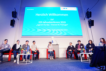 Diskussionsrunde vor einer großen Leinwand