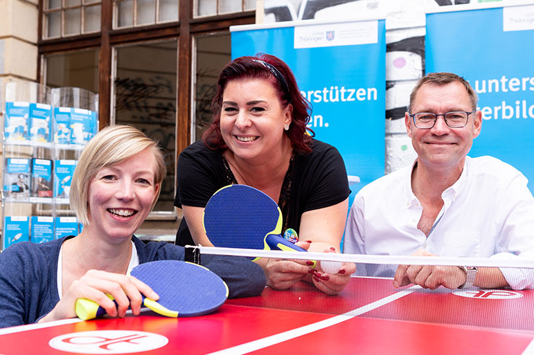 Besuchergruppe posiert an einer Tischtennisplatte