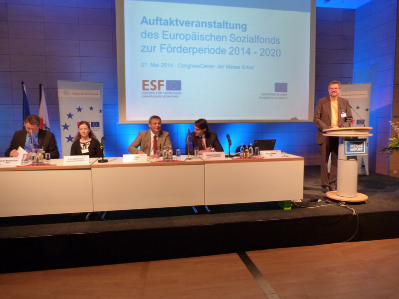 Blick auf die Bühne mit Redner, im Hintergrund das Präsentationschart "Auftaktveranstaltung des ESF zur Förderperiode 2014-2020"