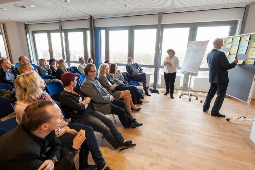 Workshop-Situation: Ein Teilnehmer heftet Notizen an ein schwarzes Brett.