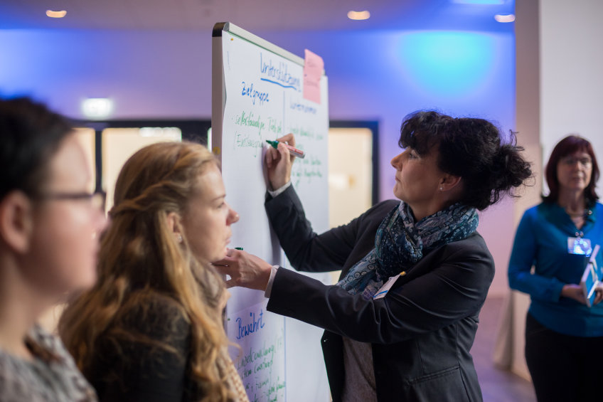 Frau schreibt etwas auf ein Flipchart